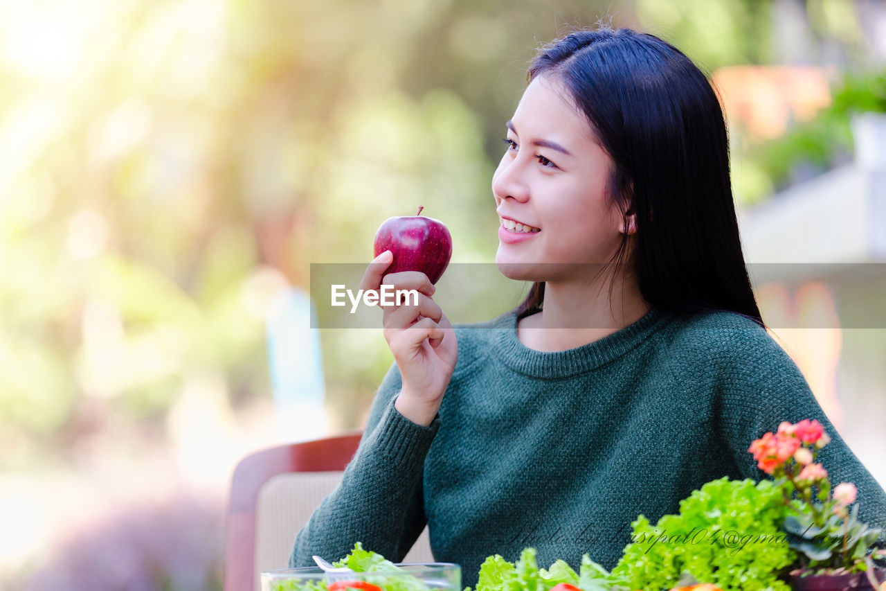 Smiling young woman having apple