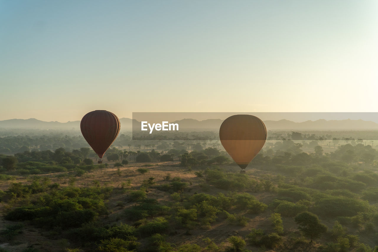 Hot air balloon flying over landscape against clear sky