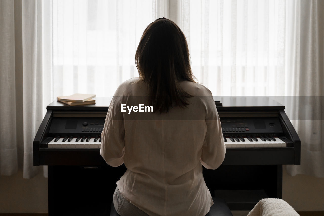 Young woman playing piano at home