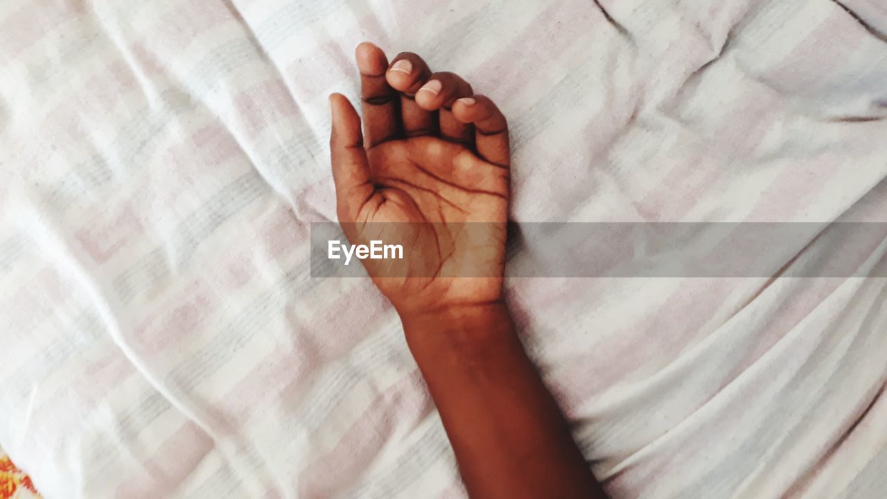 Close-up of  hand on bed