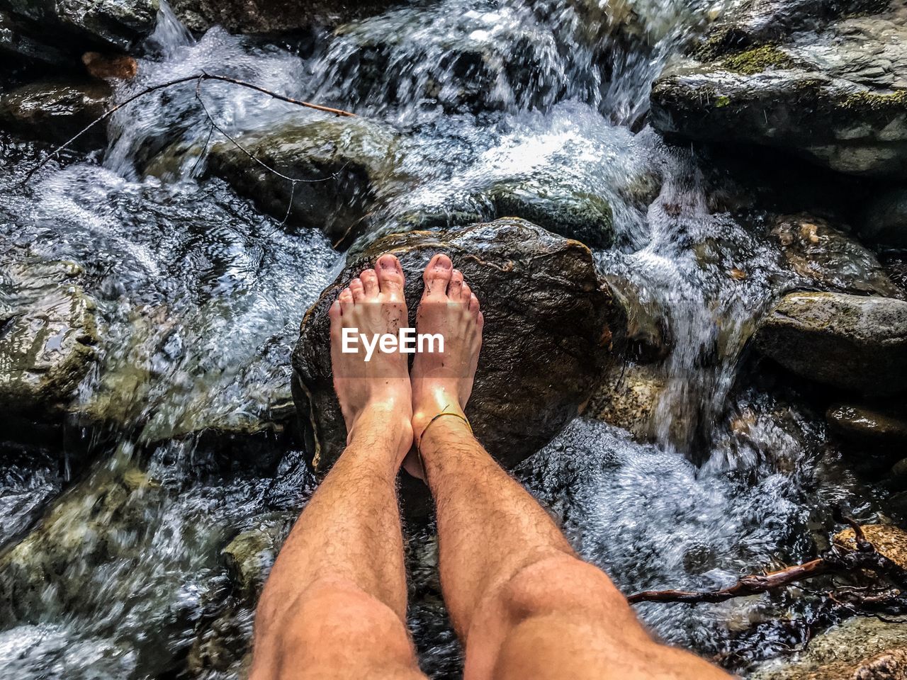 Low section of man on rock in stream