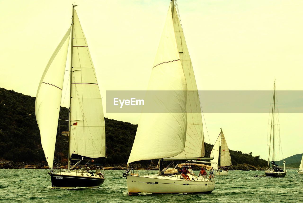 BOATS SAILING ON SEA AGAINST SKY