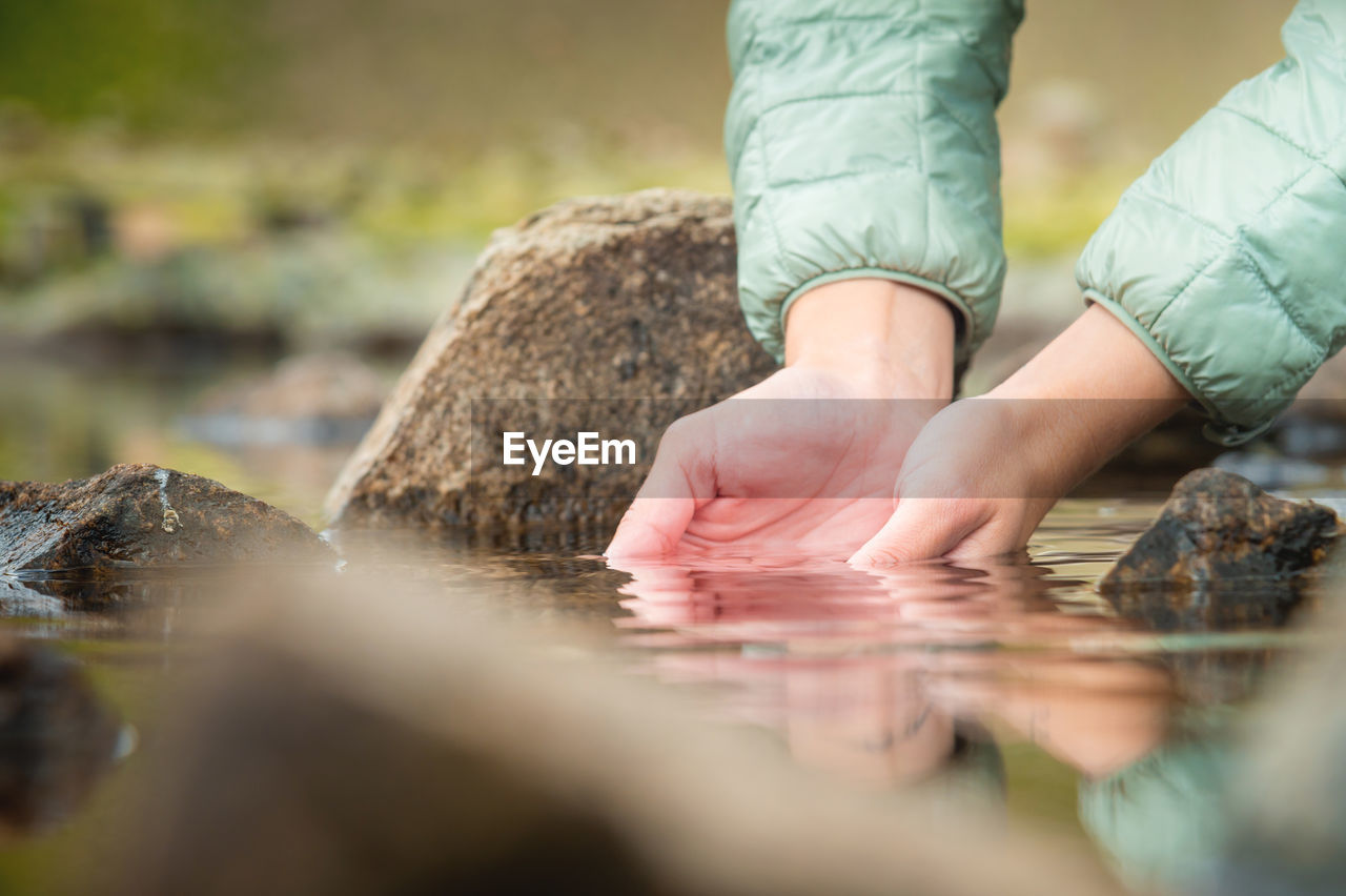 Close-up of a girl's hands and water from a mountain lake, nature, a clean source of water to quench