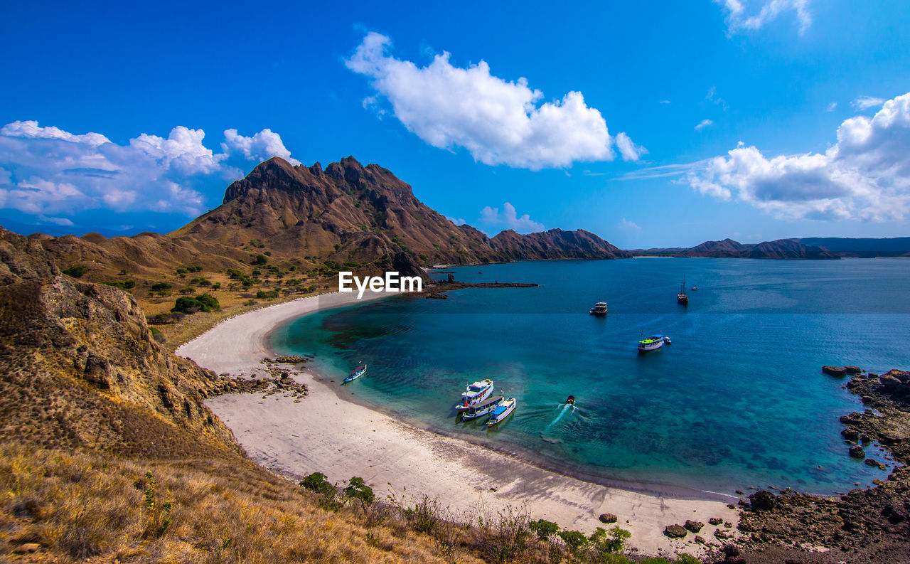Scenic view of sea and mountains against blue sky on padar island, indonesia
