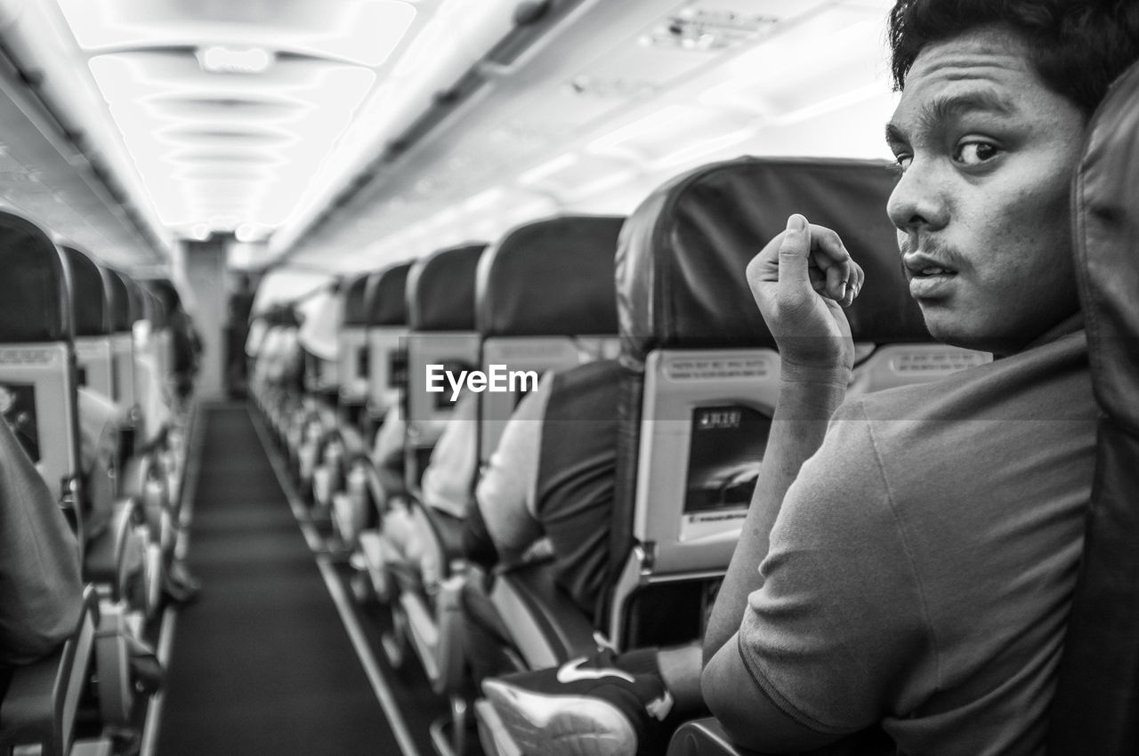 Rear view portrait of young man sitting in airplane