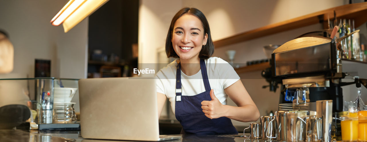 portrait of young woman using mobile phone while sitting on table at home