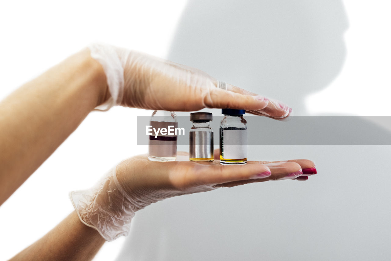 cropped hand of person holding thermometer against white background