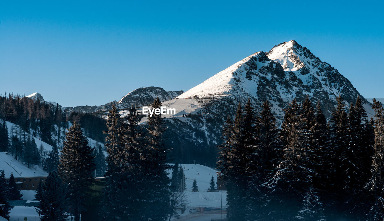 Scenic view of snowcapped mountains against clear blue sky