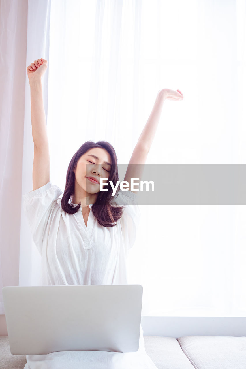 Young asian woman stretching her arms after using laptop.