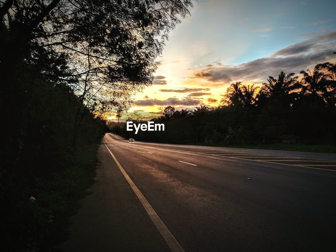 ROAD AMIDST TREES AGAINST SKY DURING SUNSET