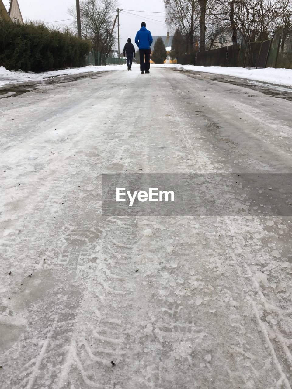 Rear view of people walking on snow covered road