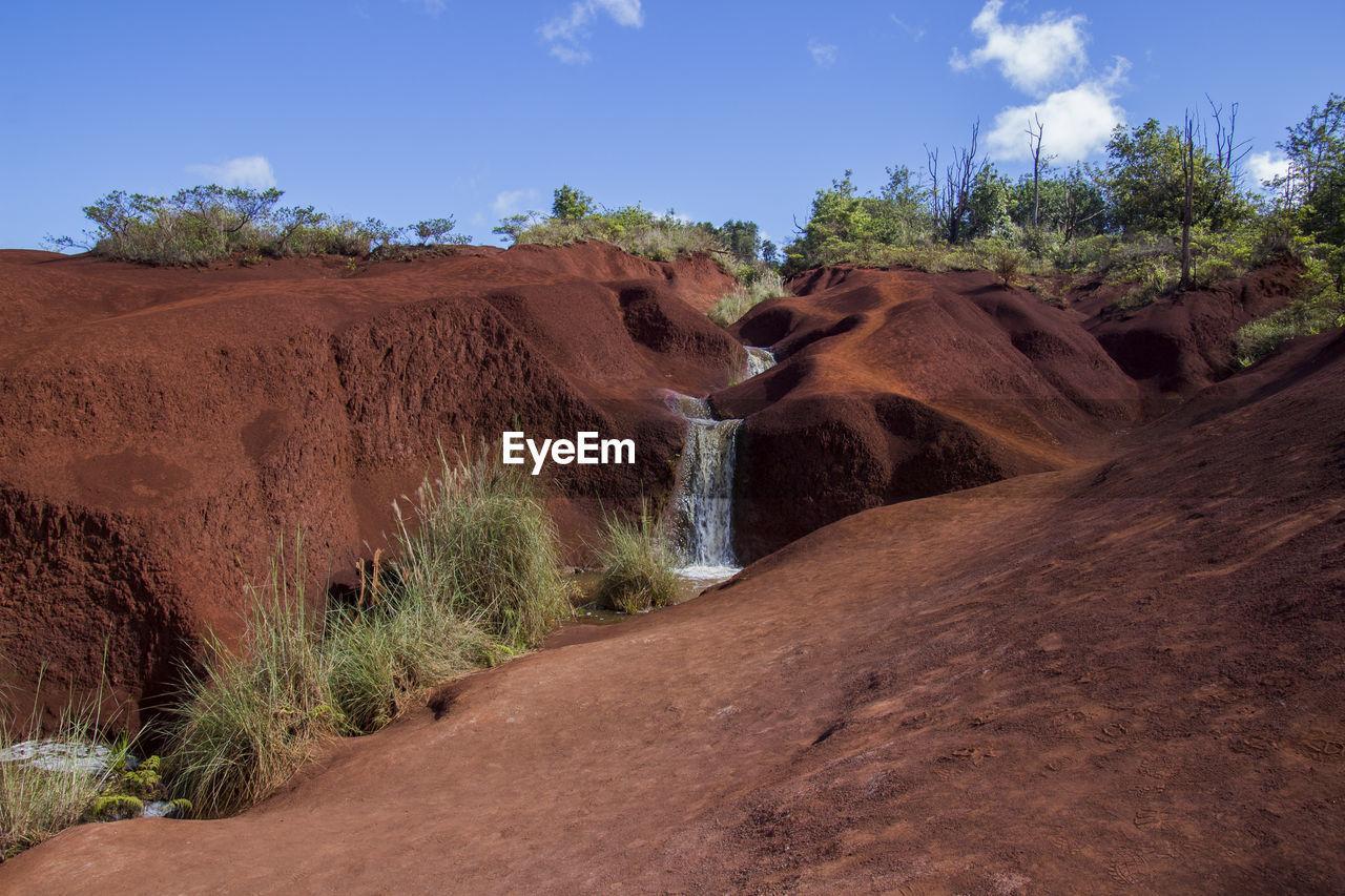 A small waterfall with a bright blue sky in the background. photographed in waimea canyon state park