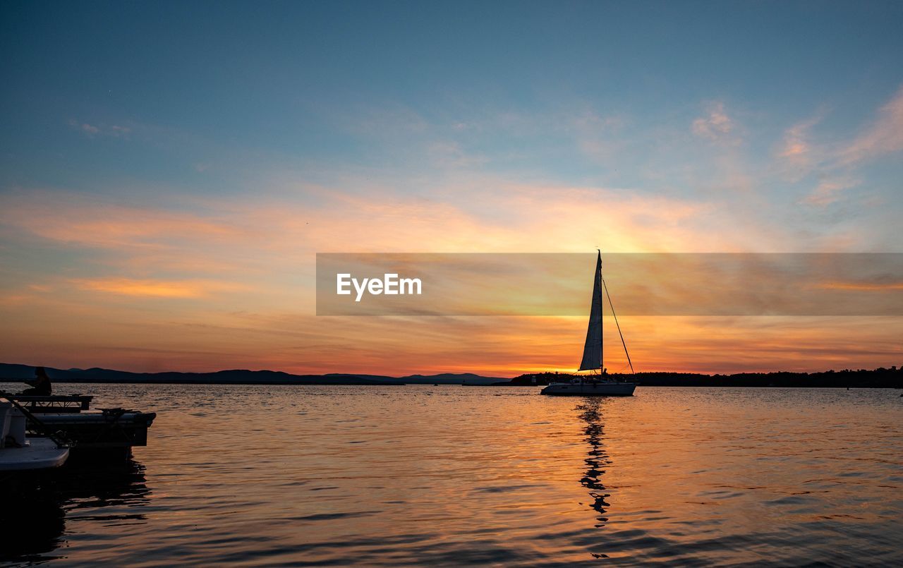 Sailboat sailing on sea against sky during sunset