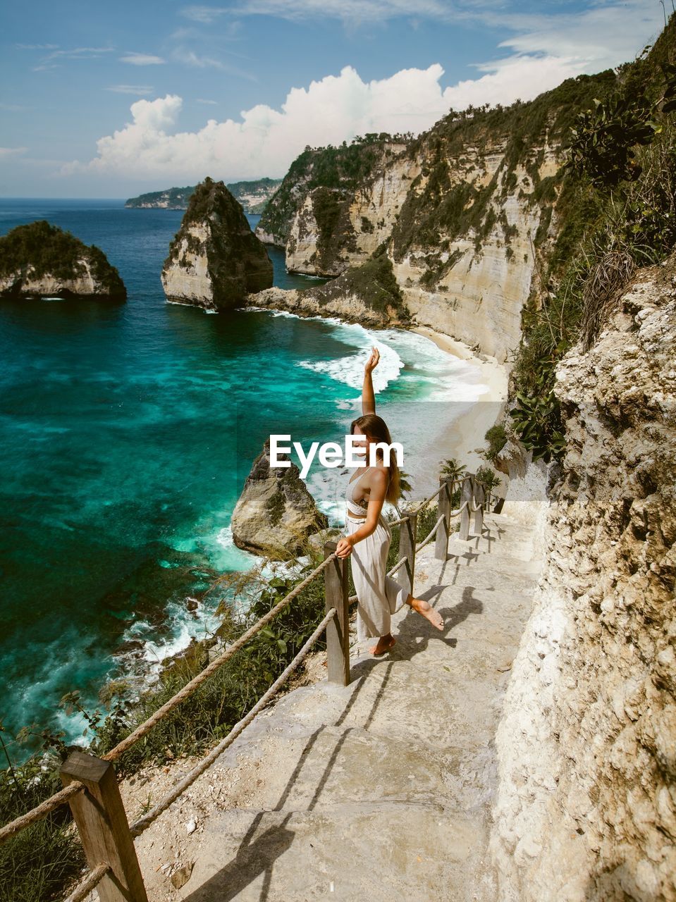 High angle view of young woman standing on rock looking at sea