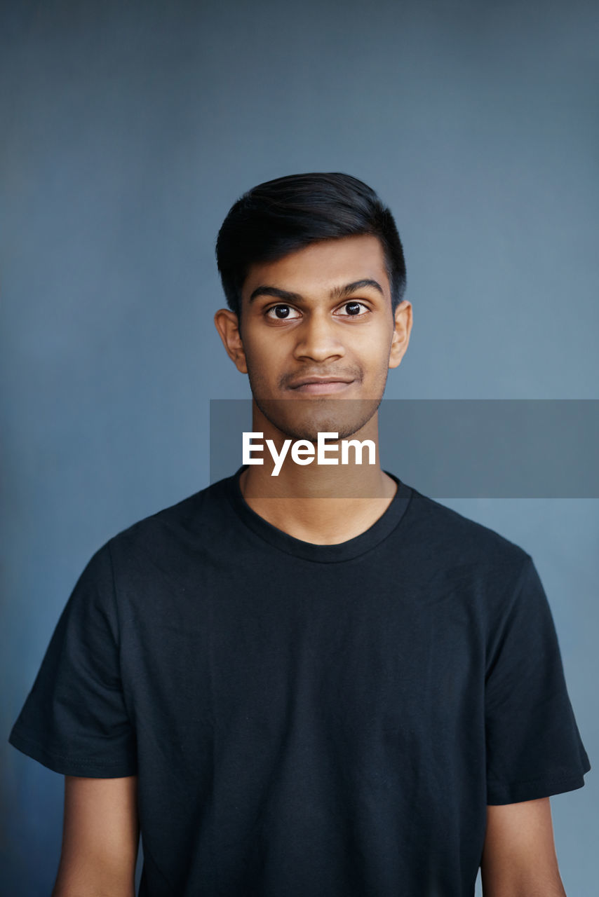 portrait of young man standing against gray background