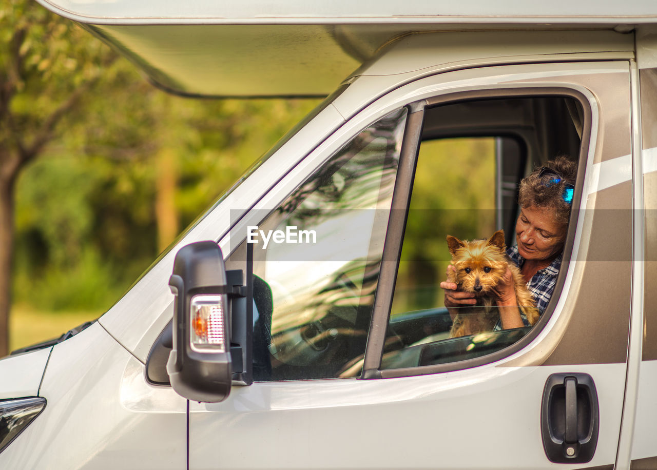 Senior woman with dog sitting in truck