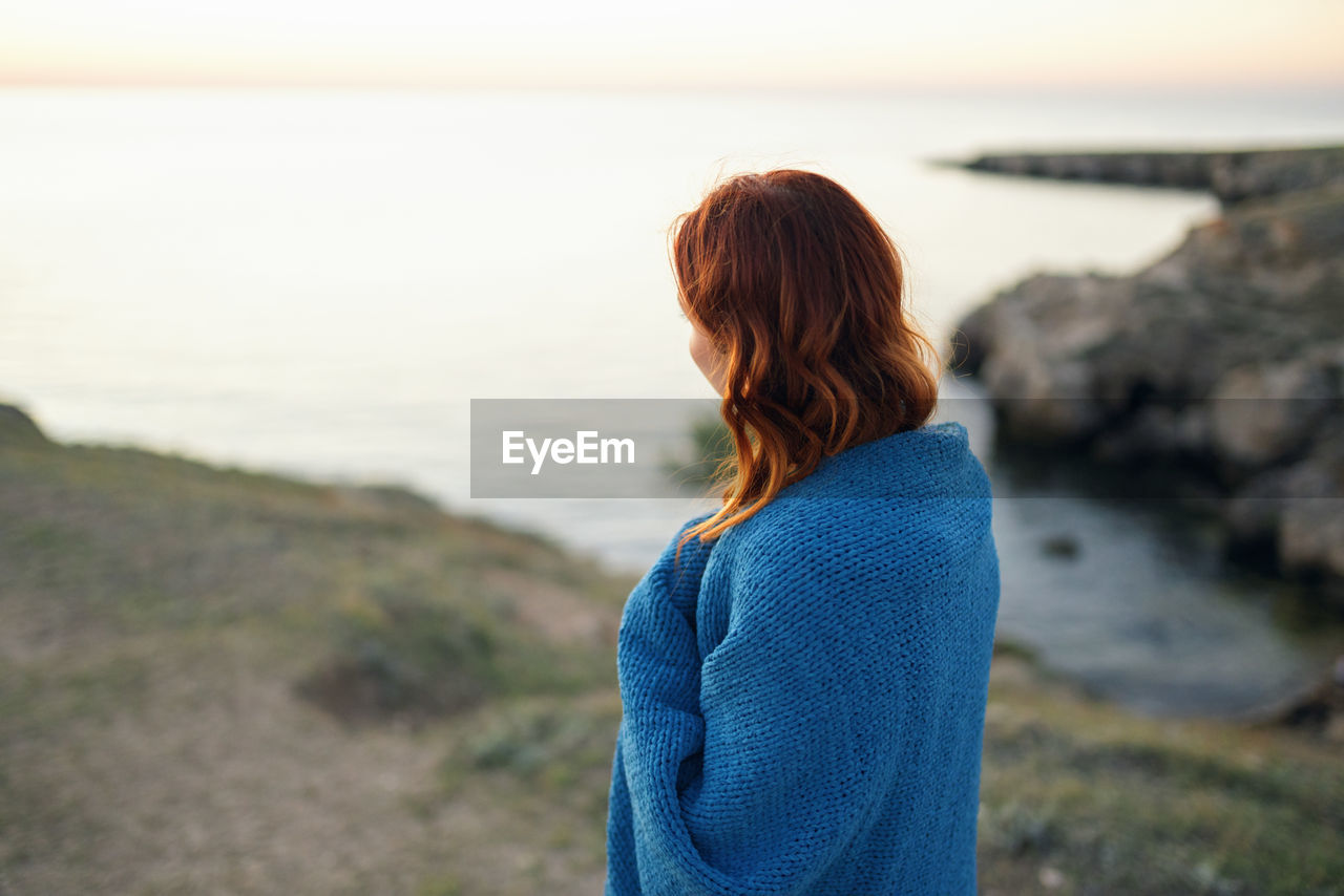 REAR VIEW OF WOMAN STANDING AT BEACH