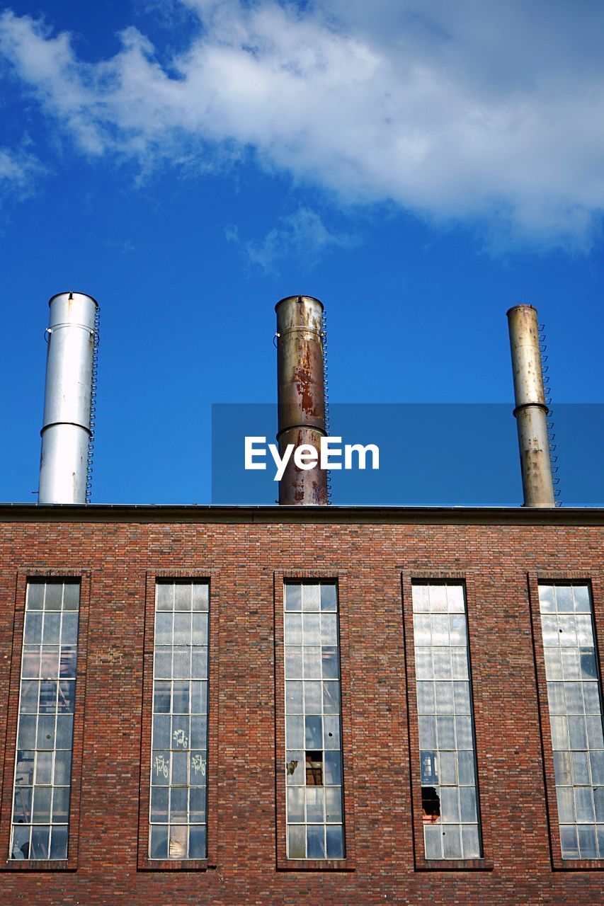 LOW ANGLE VIEW OF FACTORY AGAINST BLUE SKY