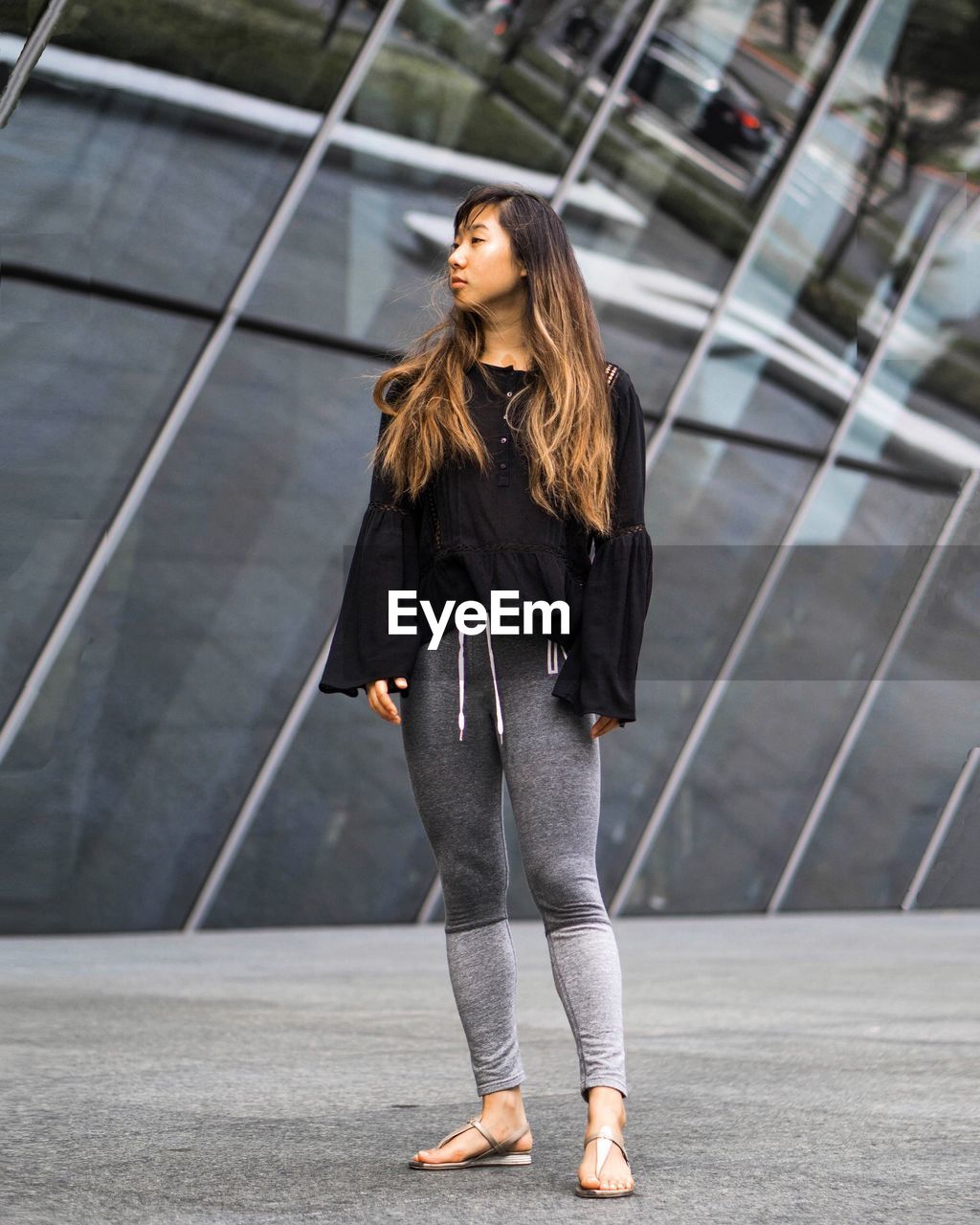 Young woman standing on footpath against building