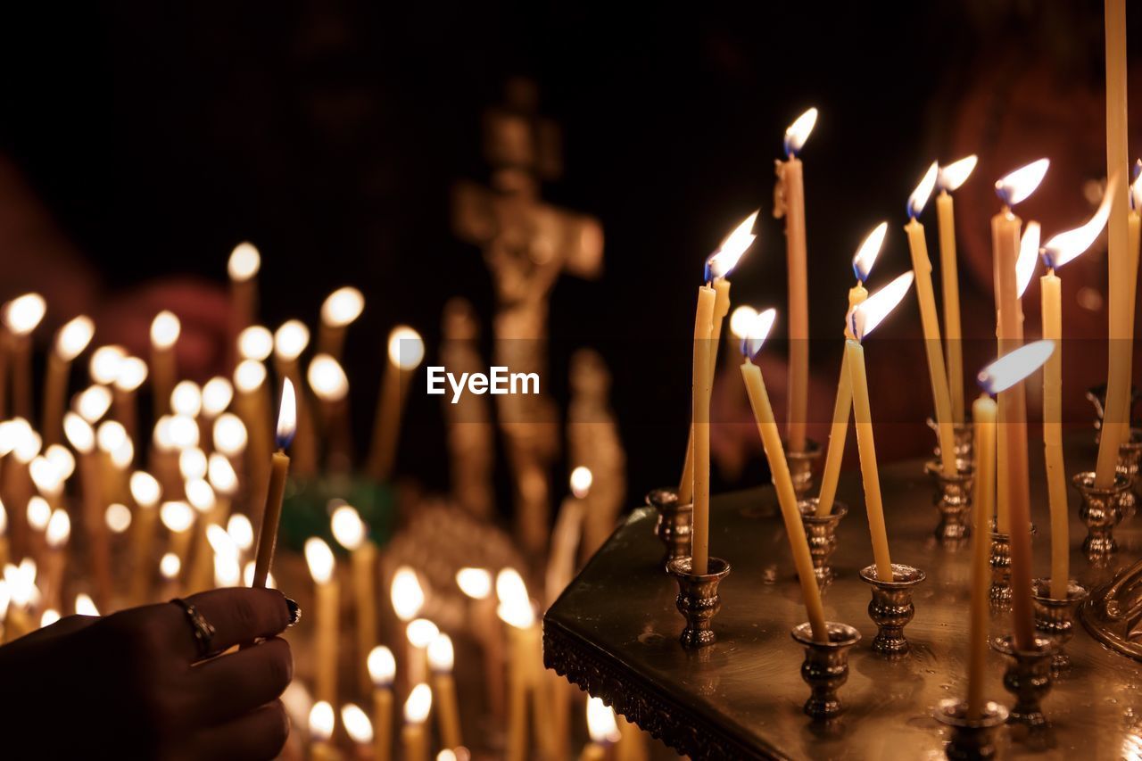 Cropped image of hand burning candles in church