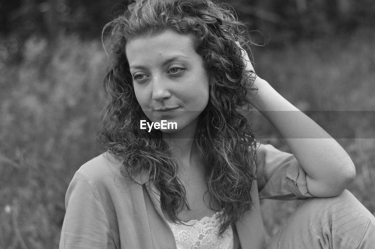 Beautiful young woman with hand in hair looking away