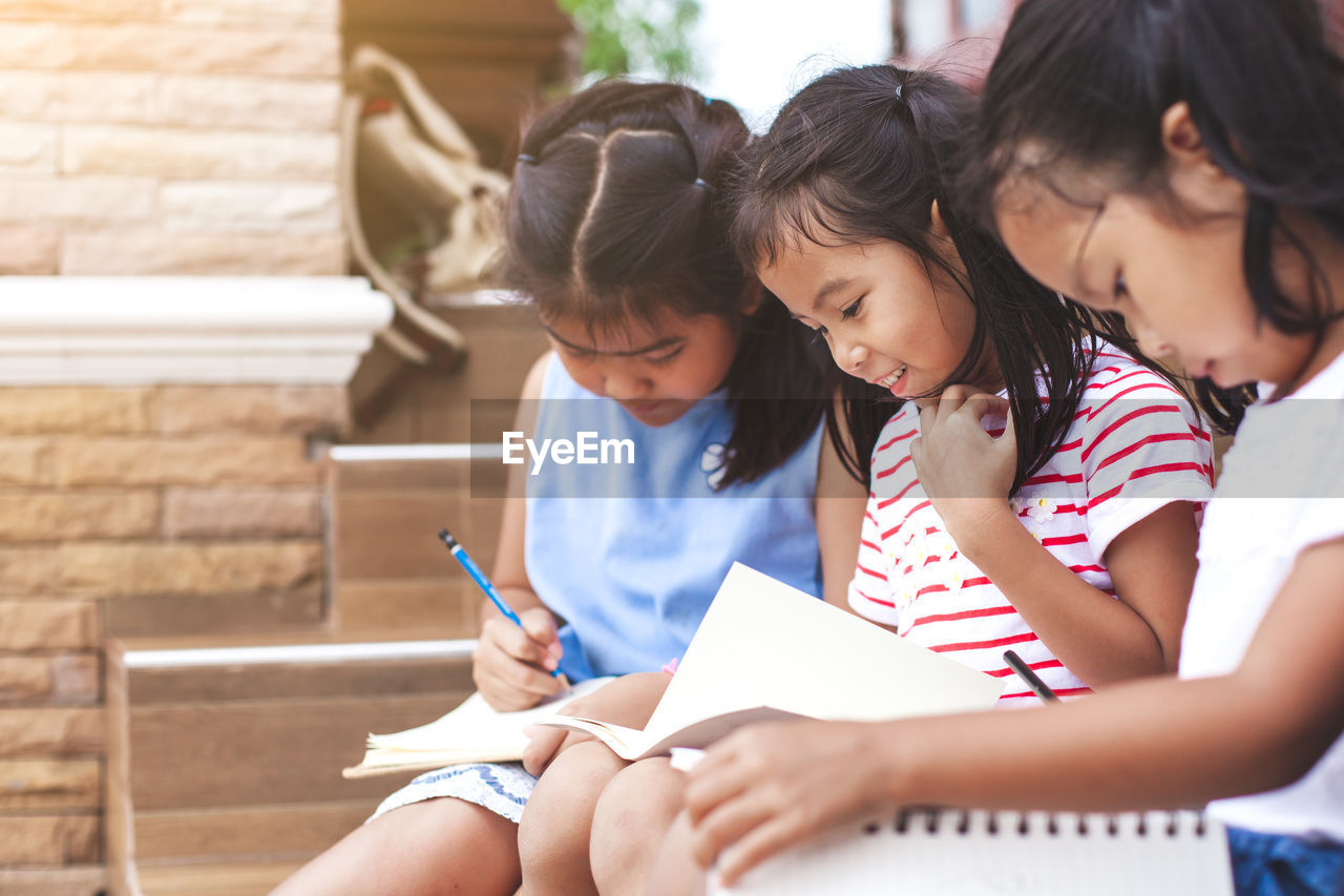 Girls studying while sitting on chair