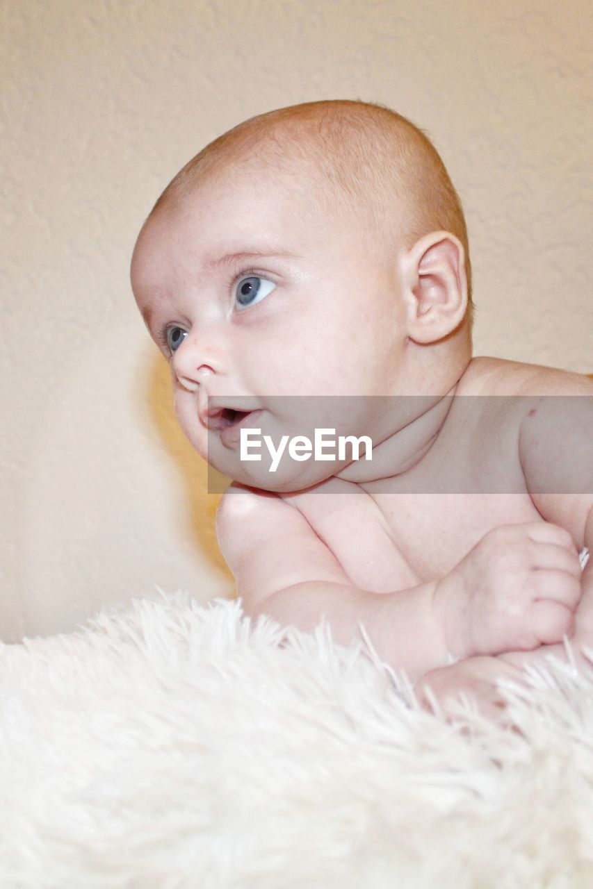 Close-up of cute baby boy against wall at home