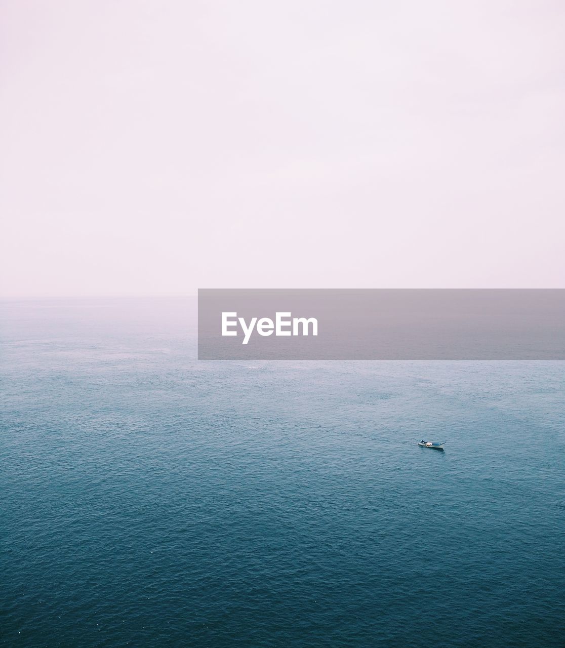 Take a photo of a boat in the middle of a blue ocean