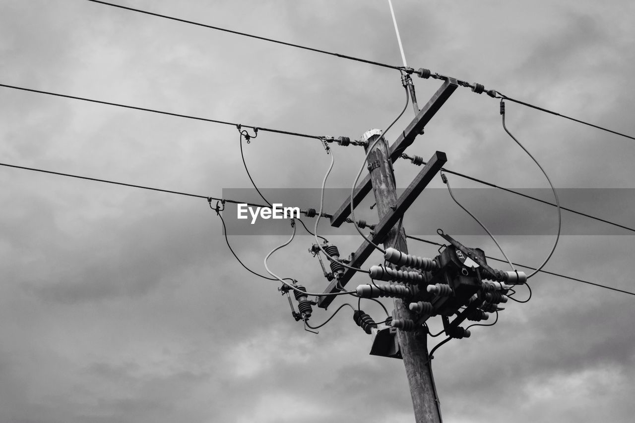 Low angle view of telephone pole against cloudy sky