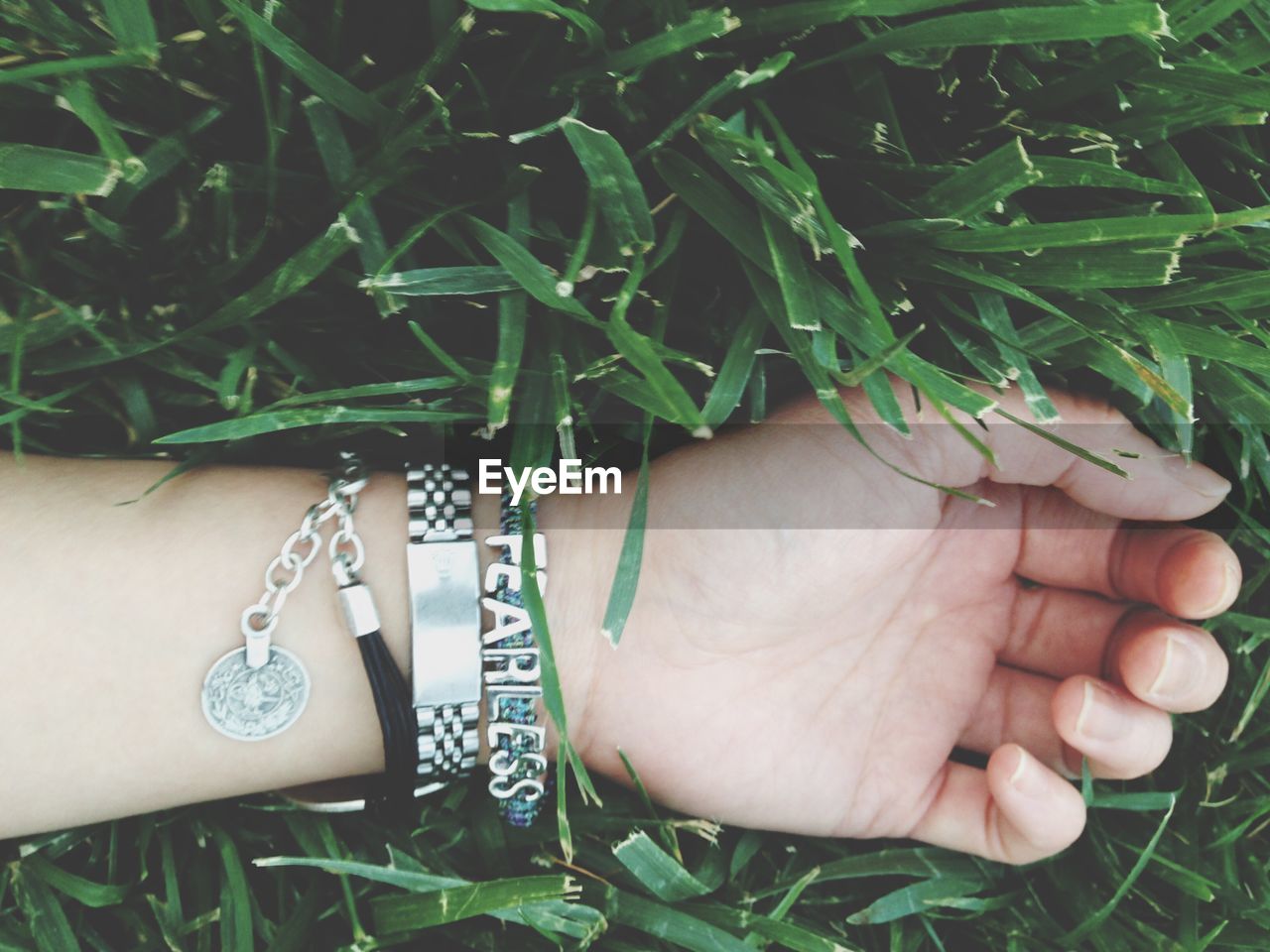 Cropped hand on woman wearing bracelet on plants