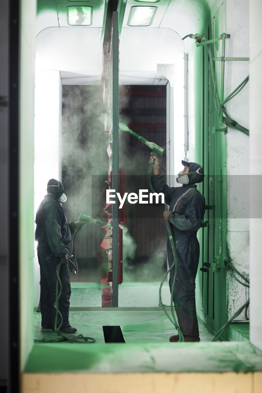 Painters spraying steel components in spray booth of a factory