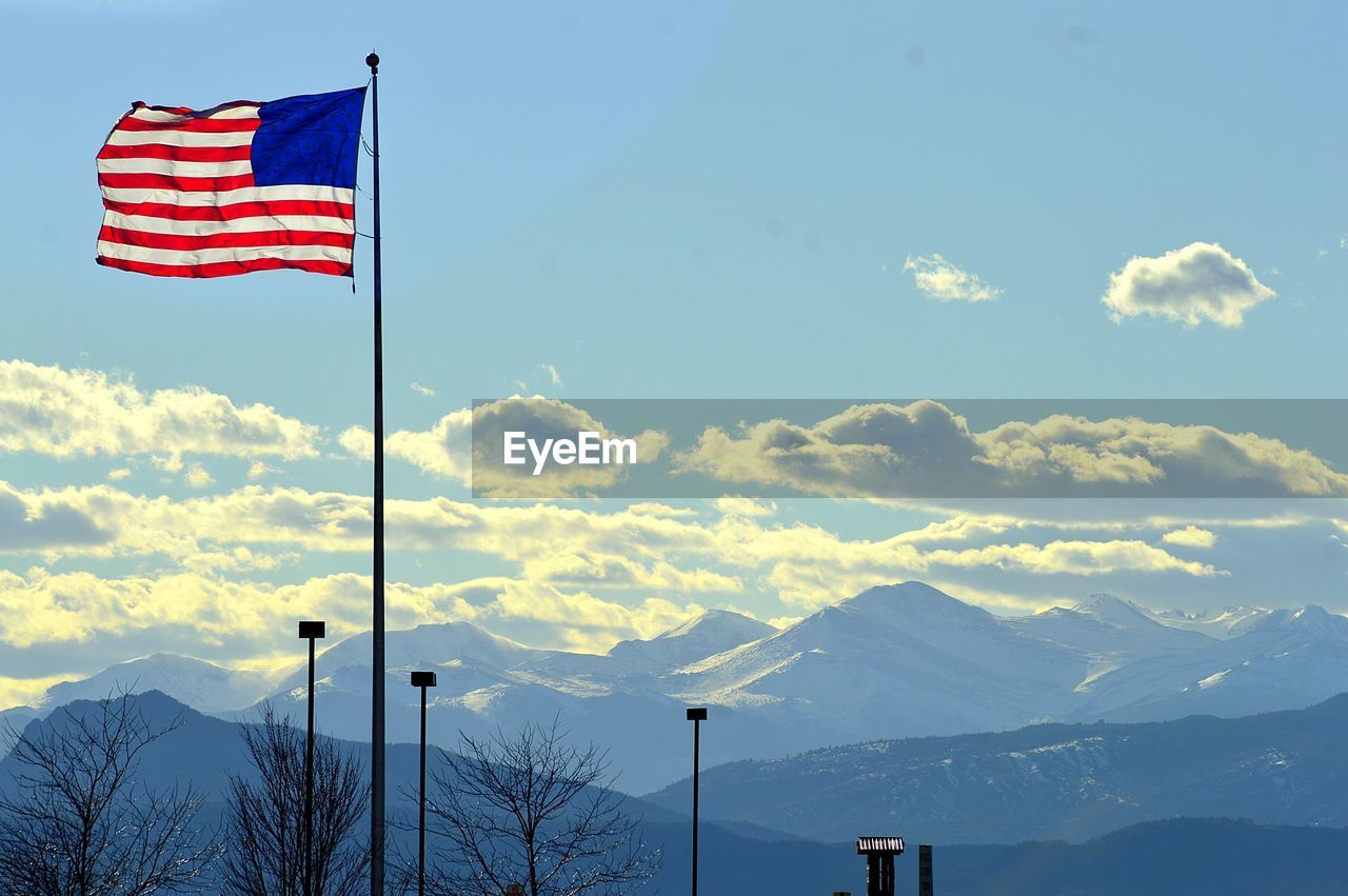 American flag by mountains against sky