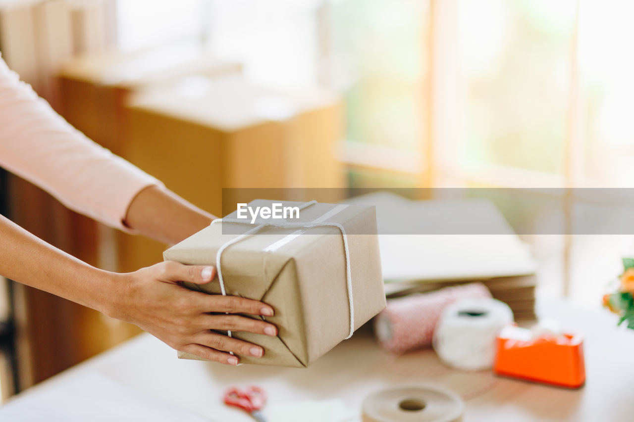 Close-up of woman holding box over table