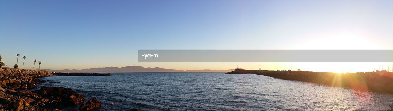 Scenic view of bay against clear sky at sunset