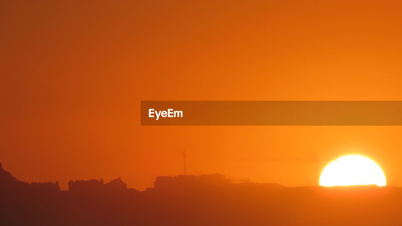 SILHOUETTE OF LANDSCAPE AGAINST ORANGE SKY