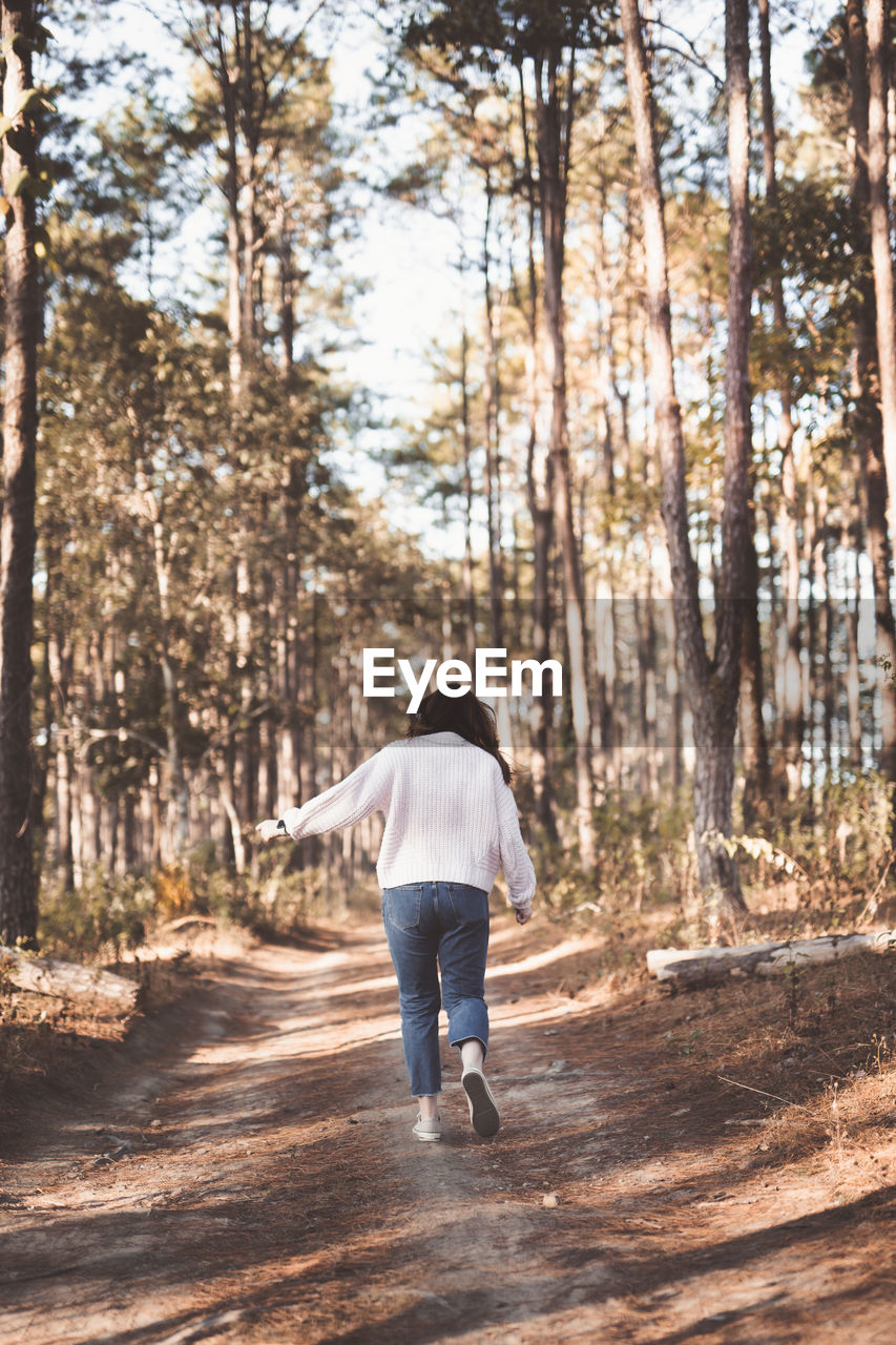 Rear view of woman walking in forest