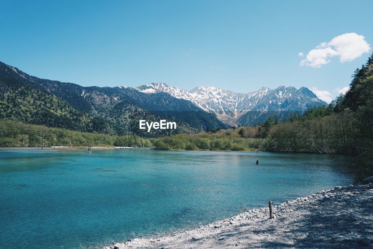 Scenic view of lake and mountains against blue sky