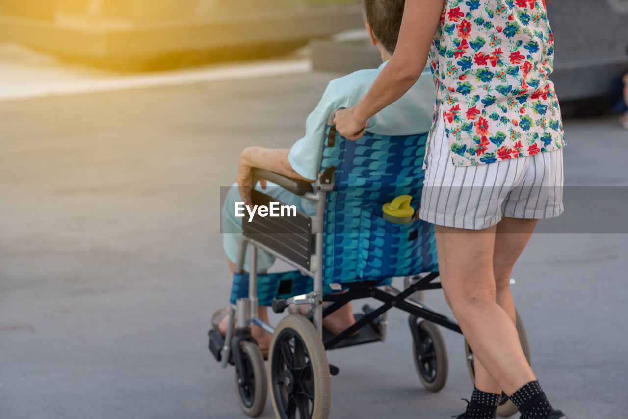 Midsection of woman pushing man on wheelchair