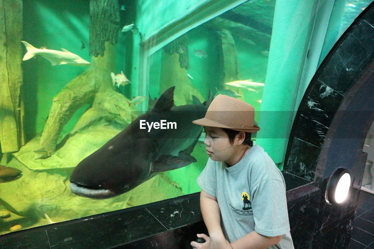 FULL LENGTH OF YOUNG WOMAN SWIMMING IN AQUARIUM