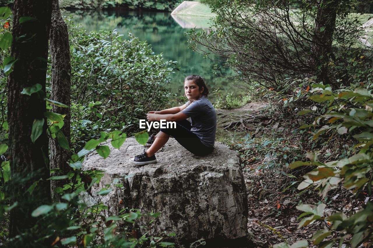 Portrait of girl sitting on rock in forest