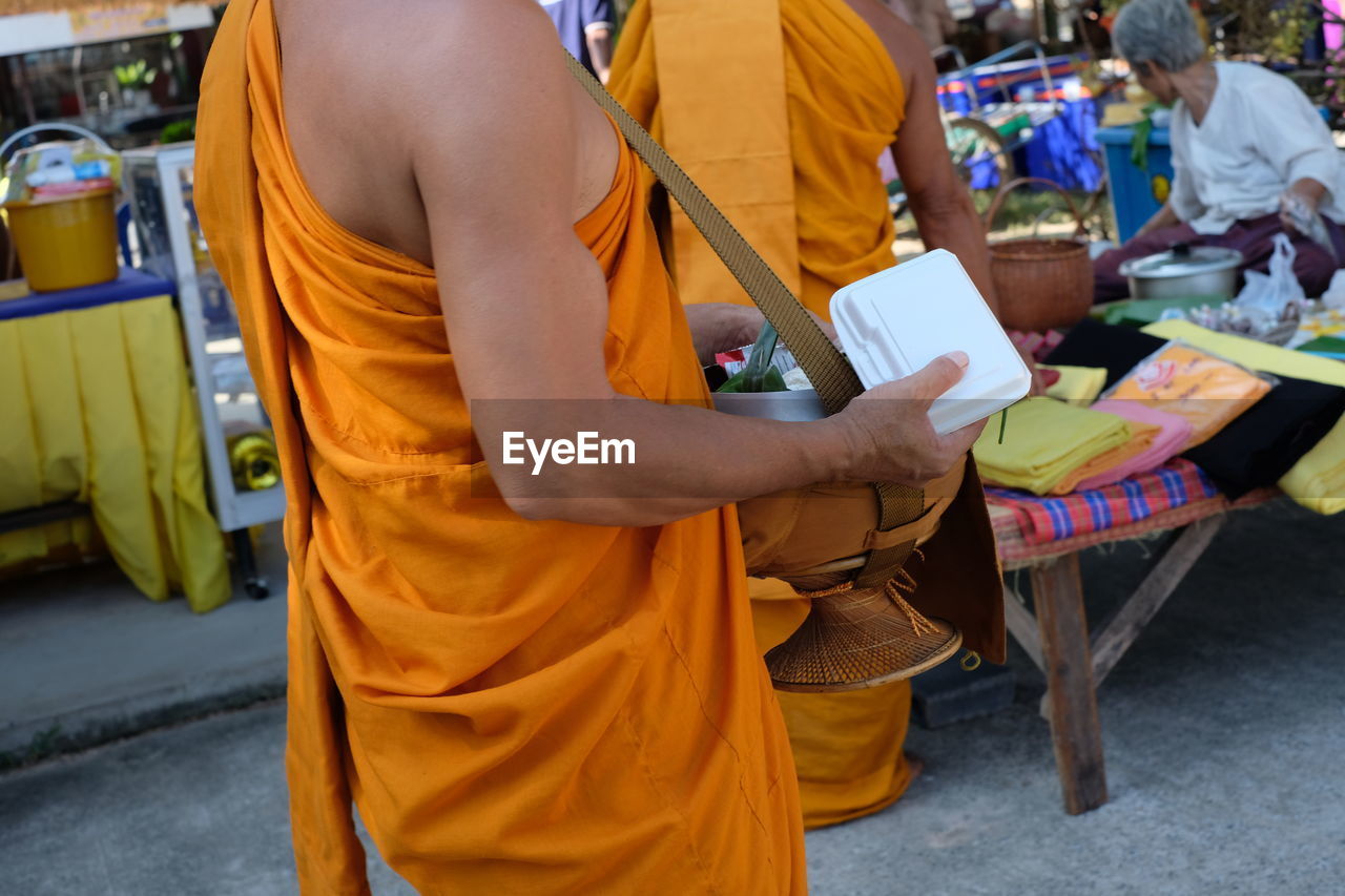 Midsection of monk standing on street