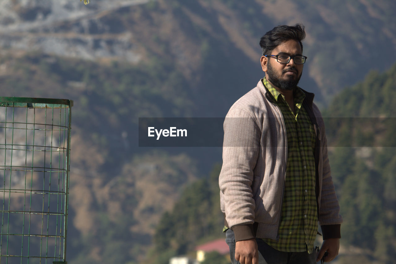 Young man standing against mountains