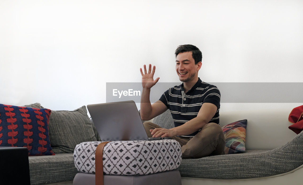 Man using laptop while sitting on sofa at home