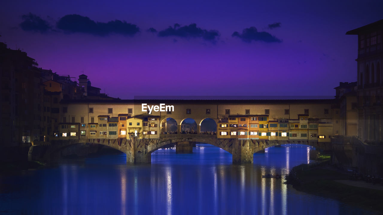 VIEW OF ARCH BRIDGE OVER RIVER AT NIGHT