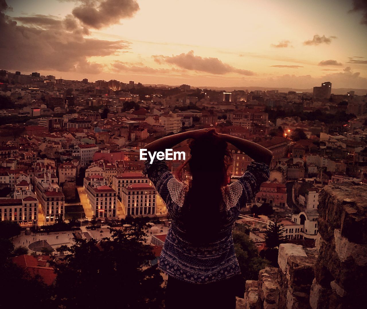 Rear view of woman looking at cityscape during sunset