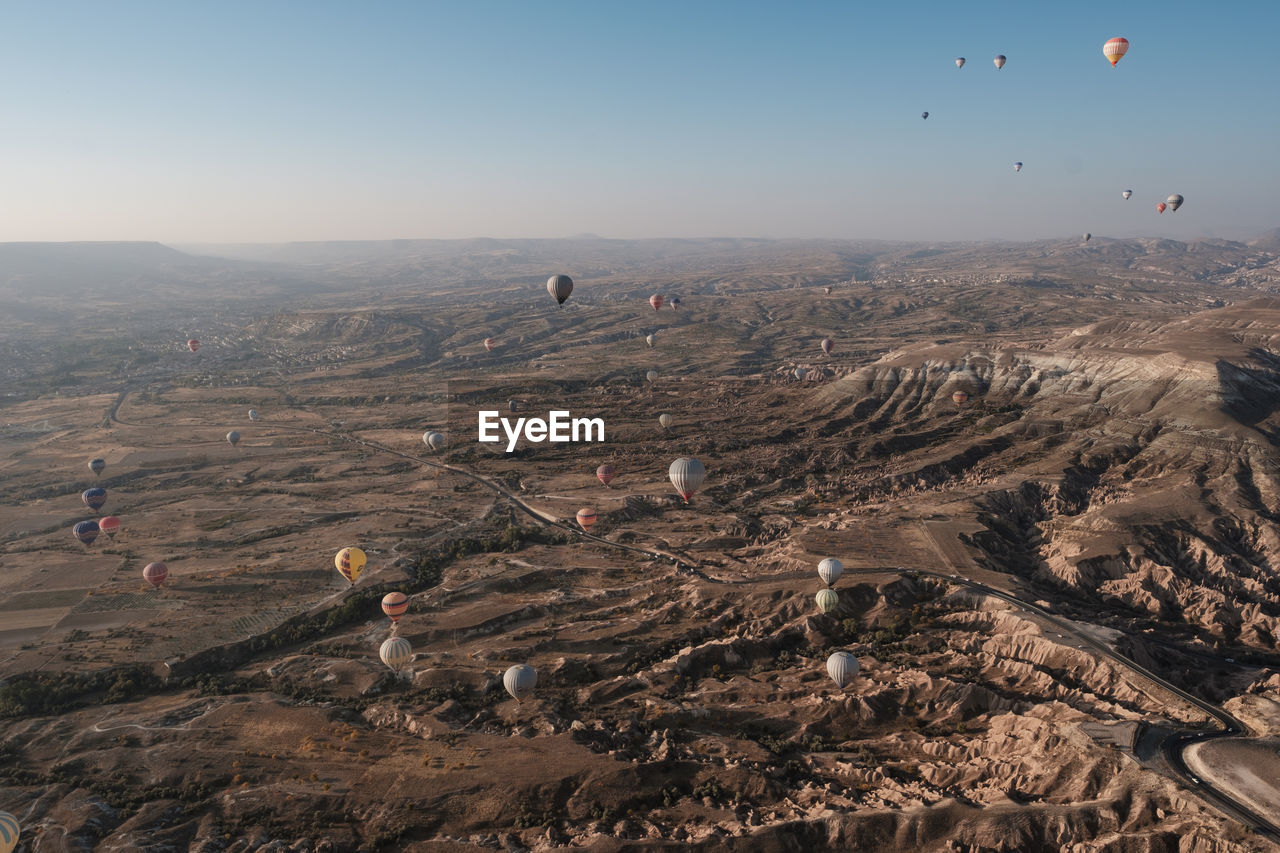 Aerial view of hot air balloons flying over dramatic landscape