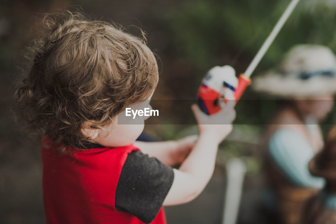 Close-up of boy holding fishing rod while standing outdoors