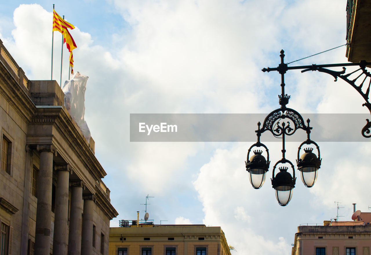 Low angle view of street light by buildings against sky