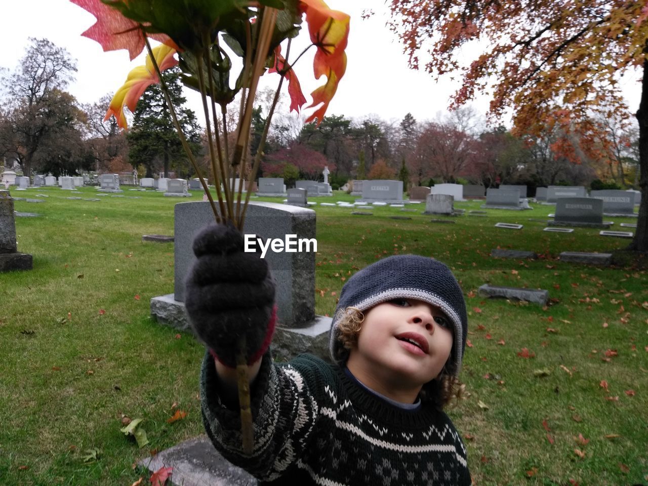 Portrait of girl with leaves standing in graveyard