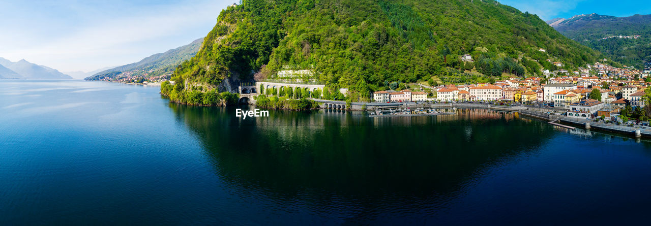 SCENIC VIEW OF LAKE AMIDST TREES AND BUILDINGS AGAINST SKY